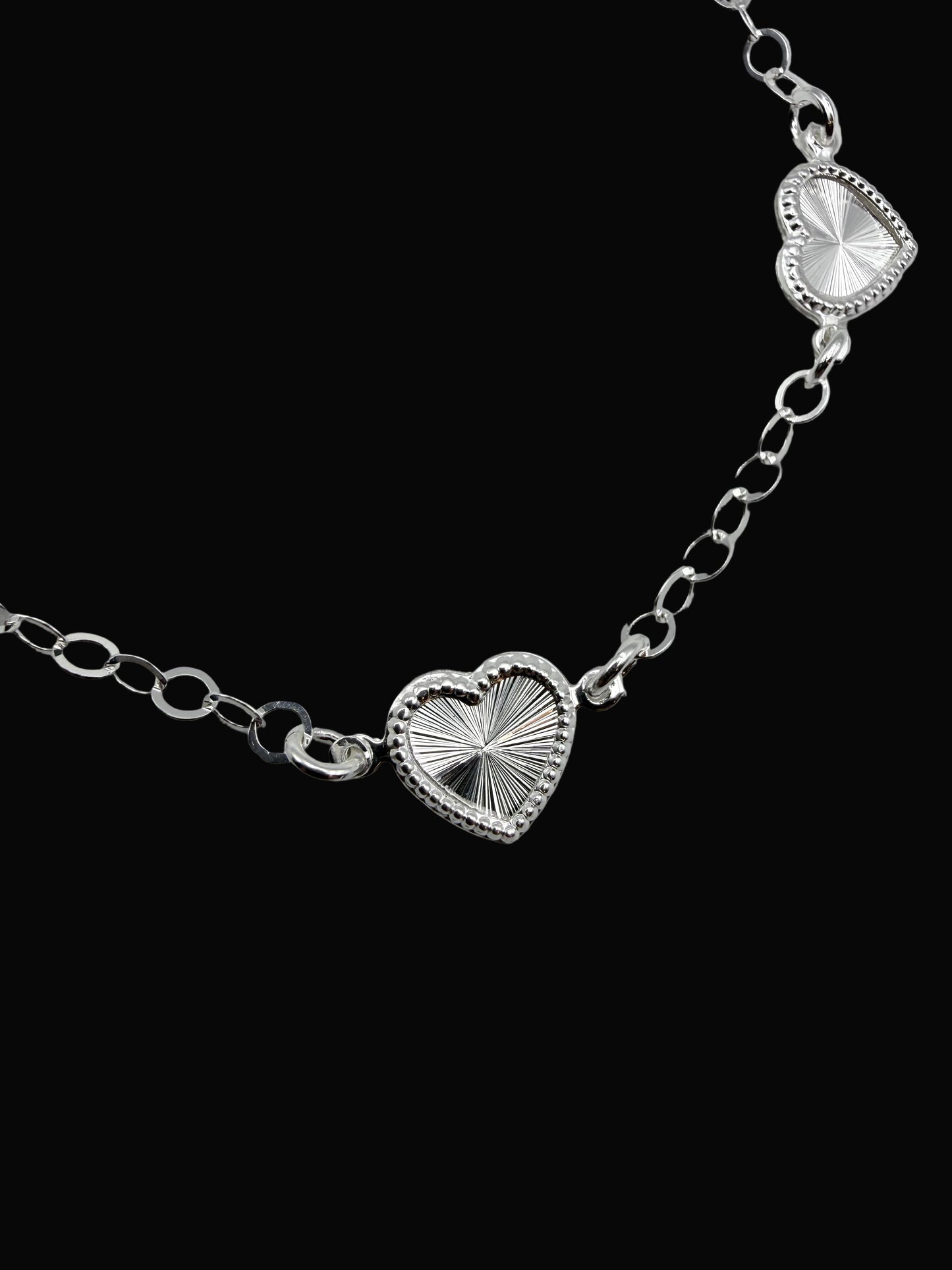 Silver bracelet with heart-shaped links on a gray background