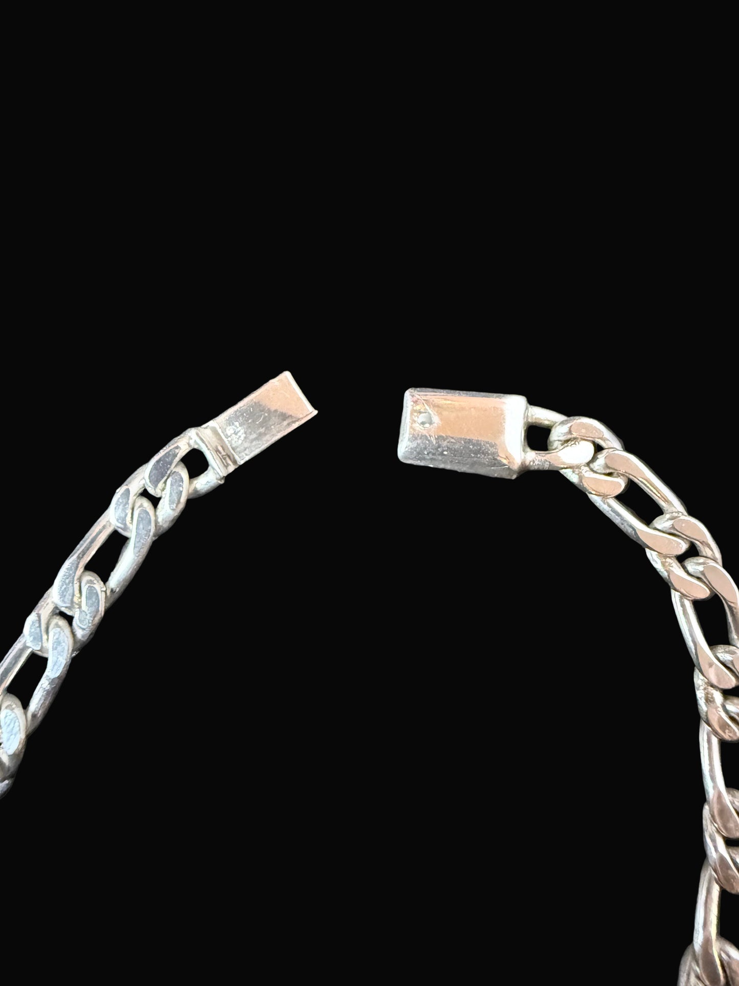 Close-up of a silver chain bracelet on a dark surface