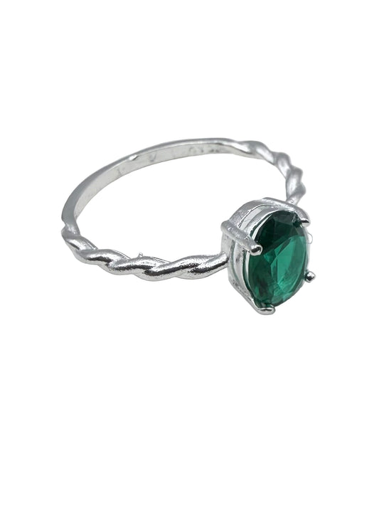 Silver ring with a green gemstone on a white surface