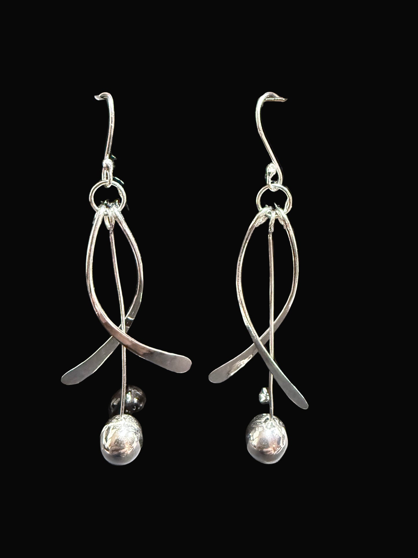 Silver earrings on a black display card against a gray background