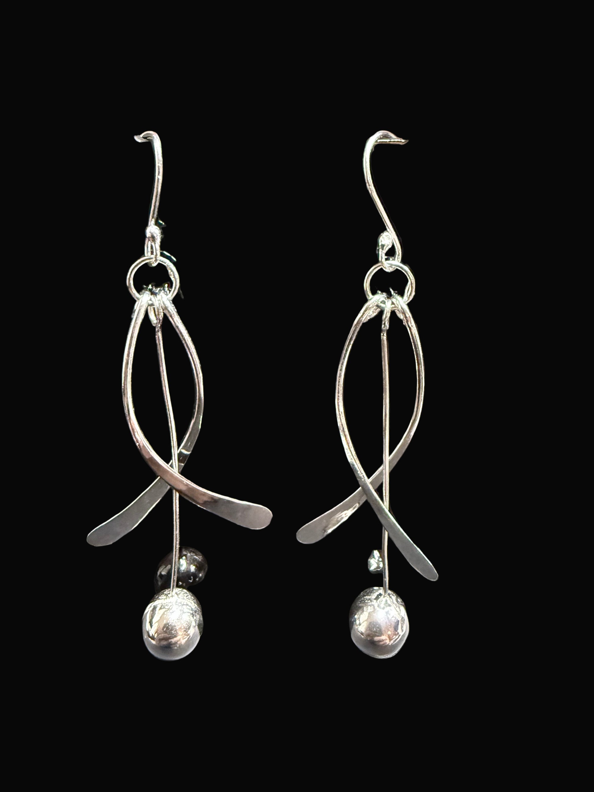 Silver earrings on a black display card against a gray background