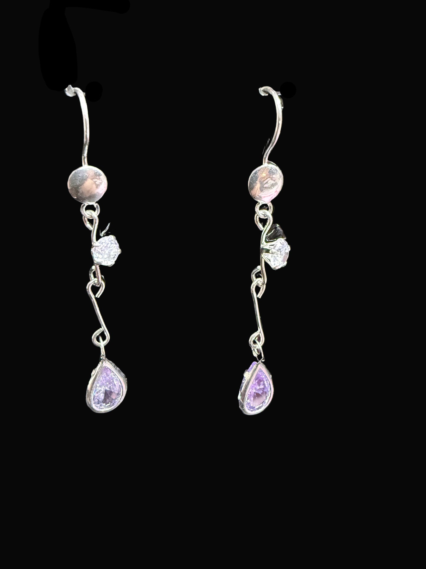 Pair of silver earrings with purple stones on a black display card.