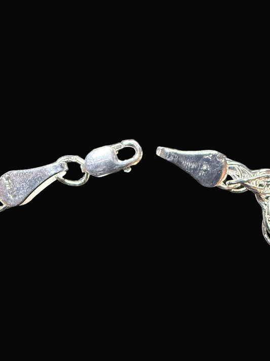 Silver chain bracelet on a textured dark surface