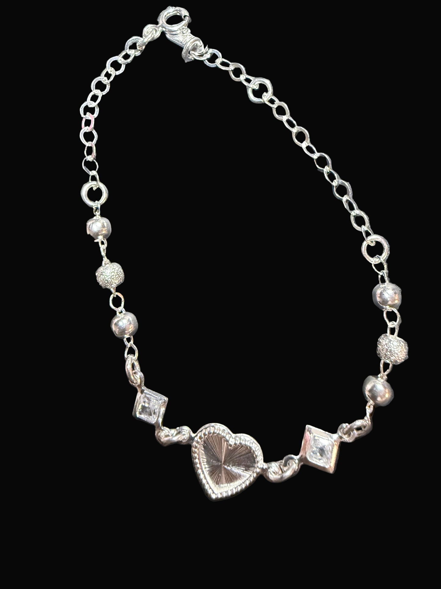 Silver bracelet with heart charm on a dark surface