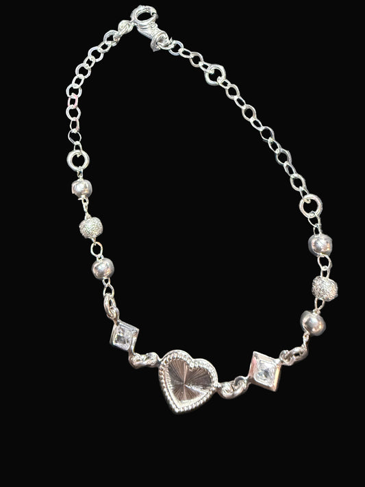 Silver bracelet with heart charm on a dark surface