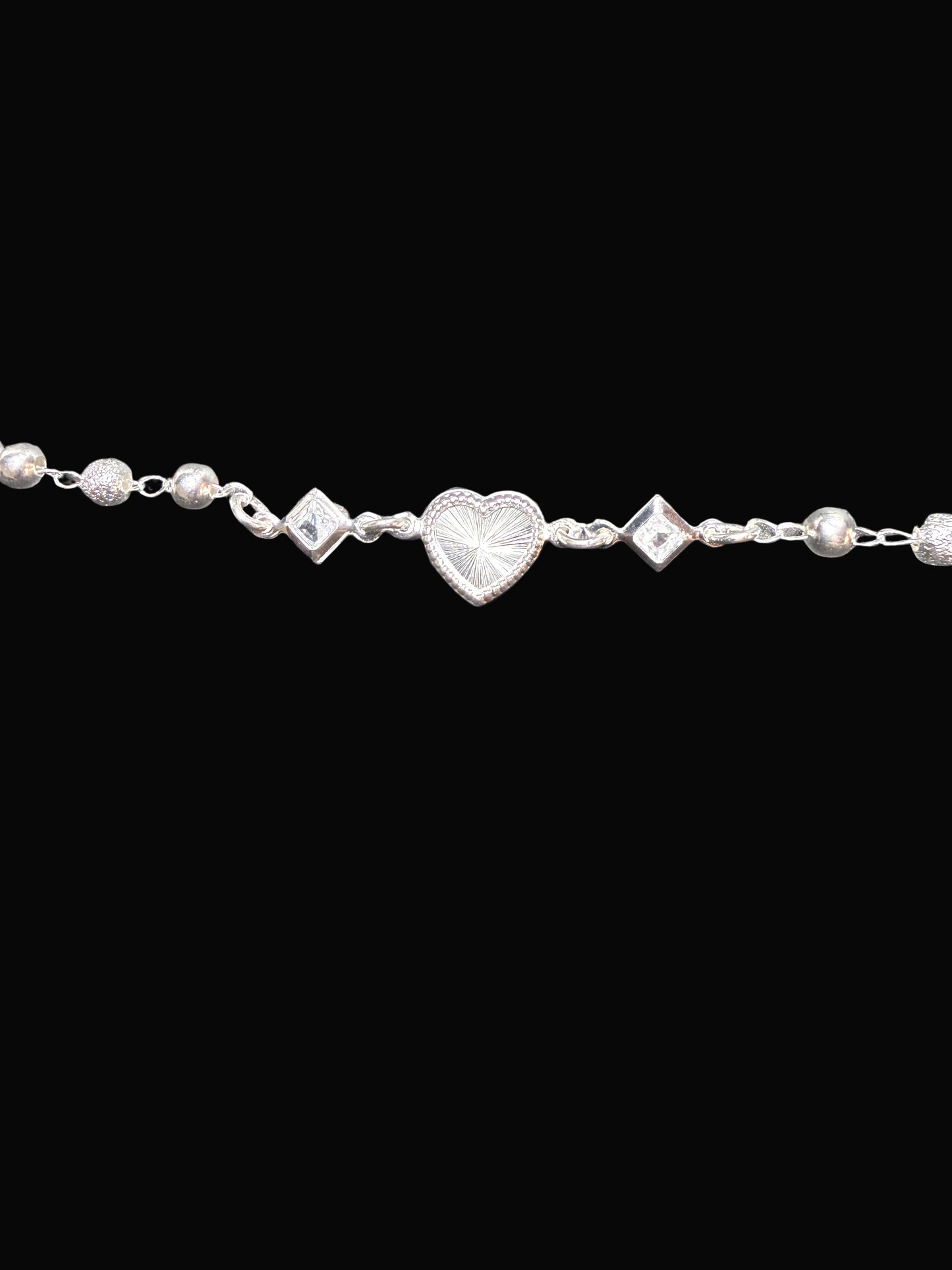 Silver bracelet with heart and diamond-shaped charms on a gray background
