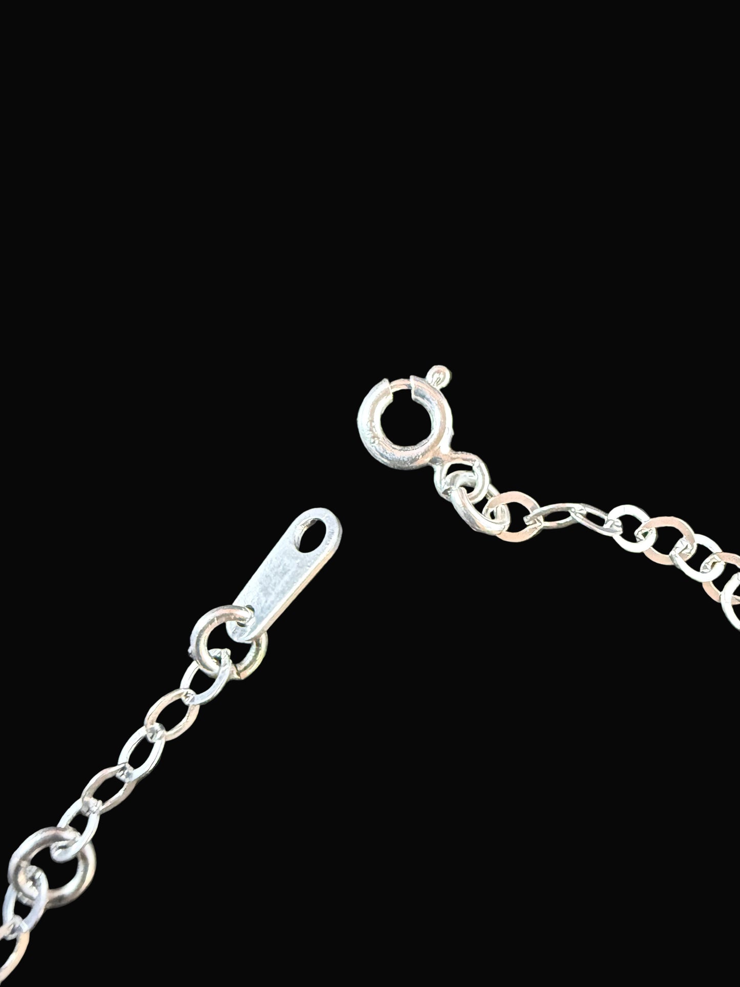 Close-up of a silver chain on a dark textured surface