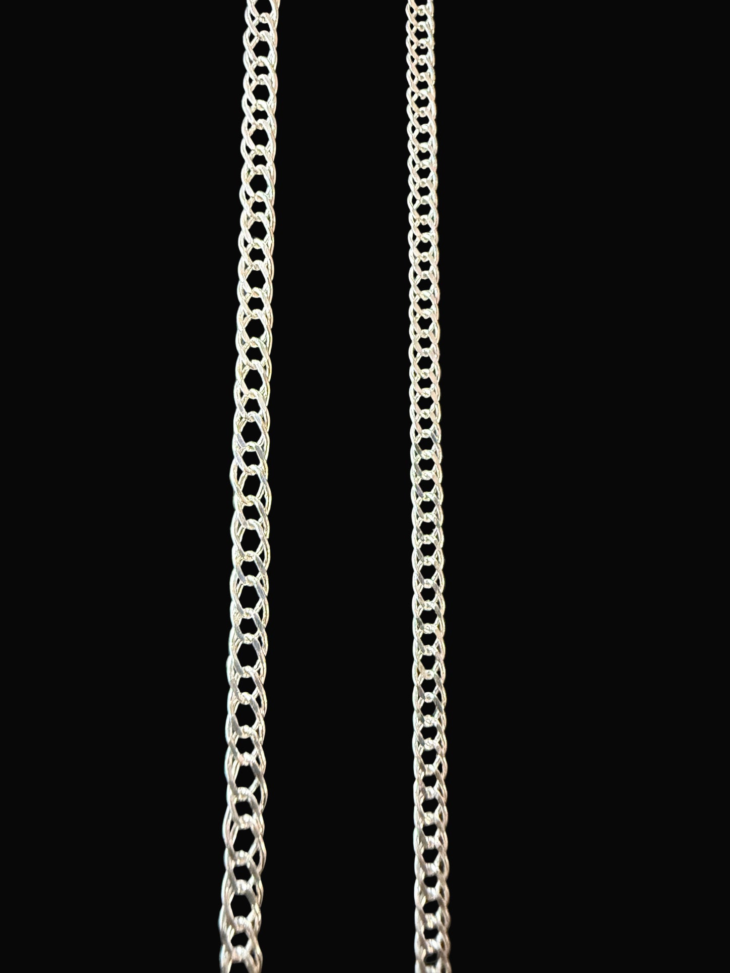 Two silver chains on a black textured surface