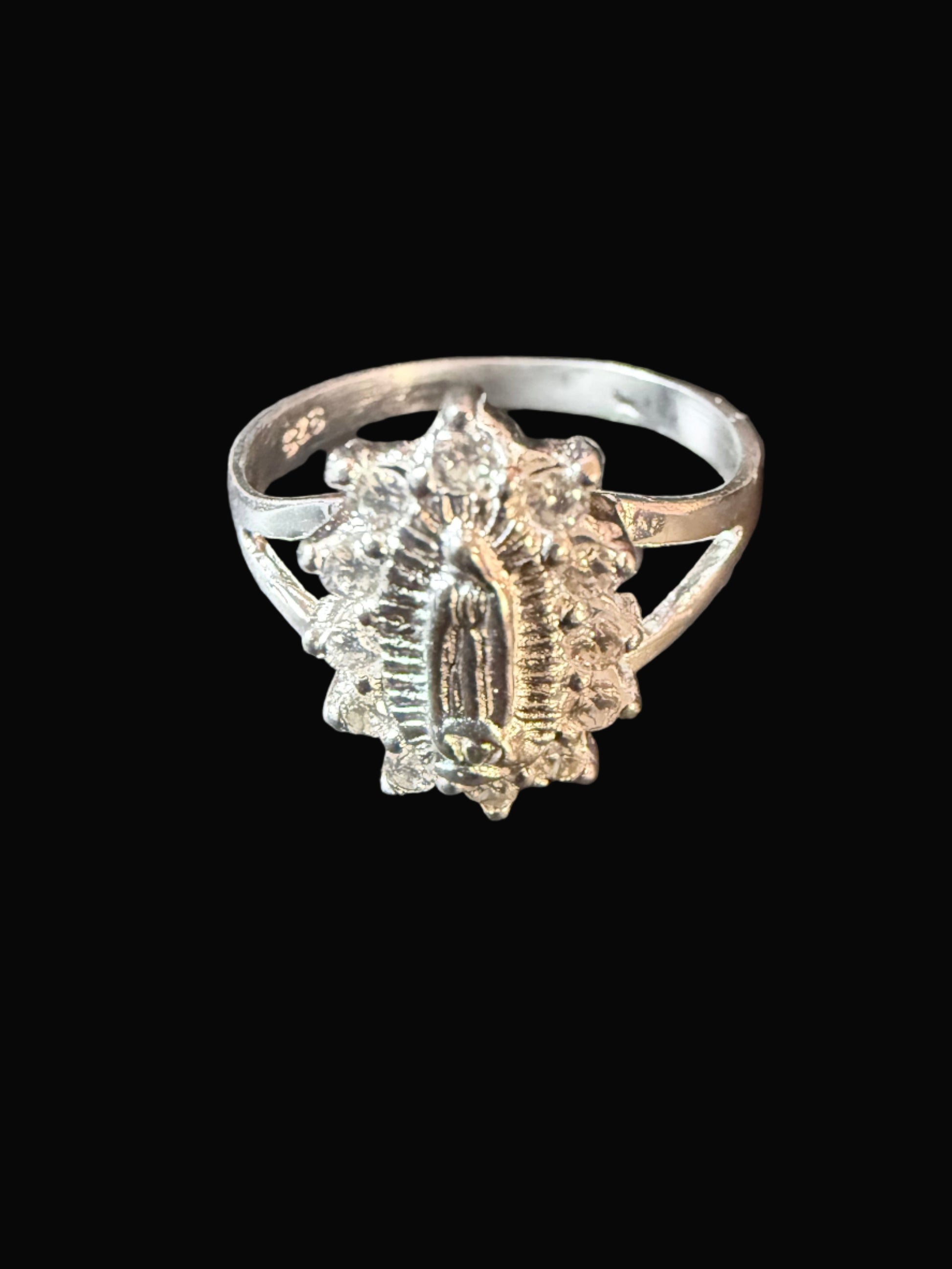 Silver ring with intricate design on a textured black surface