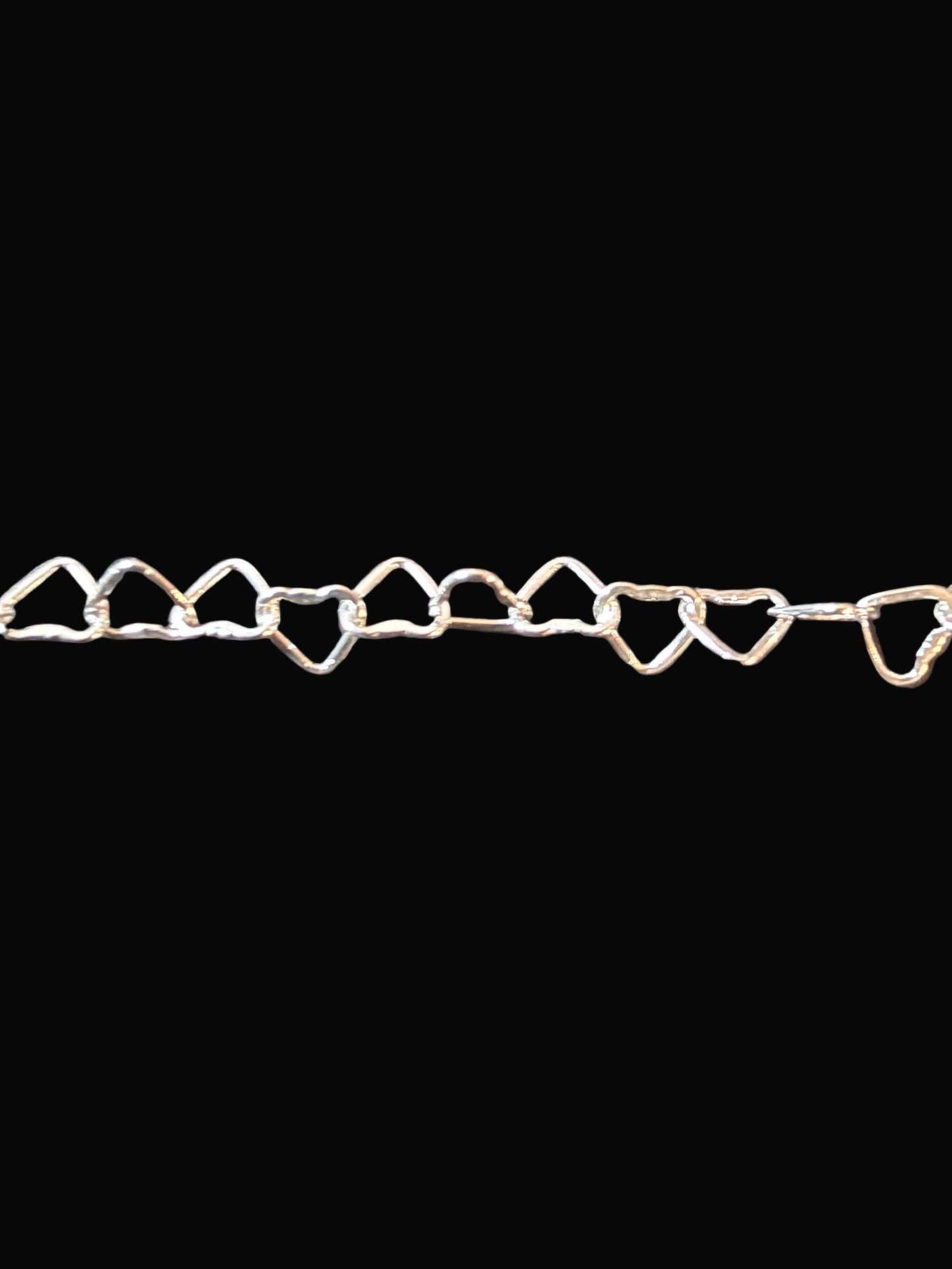 Silver heart-shaped chain on a dark textured surface