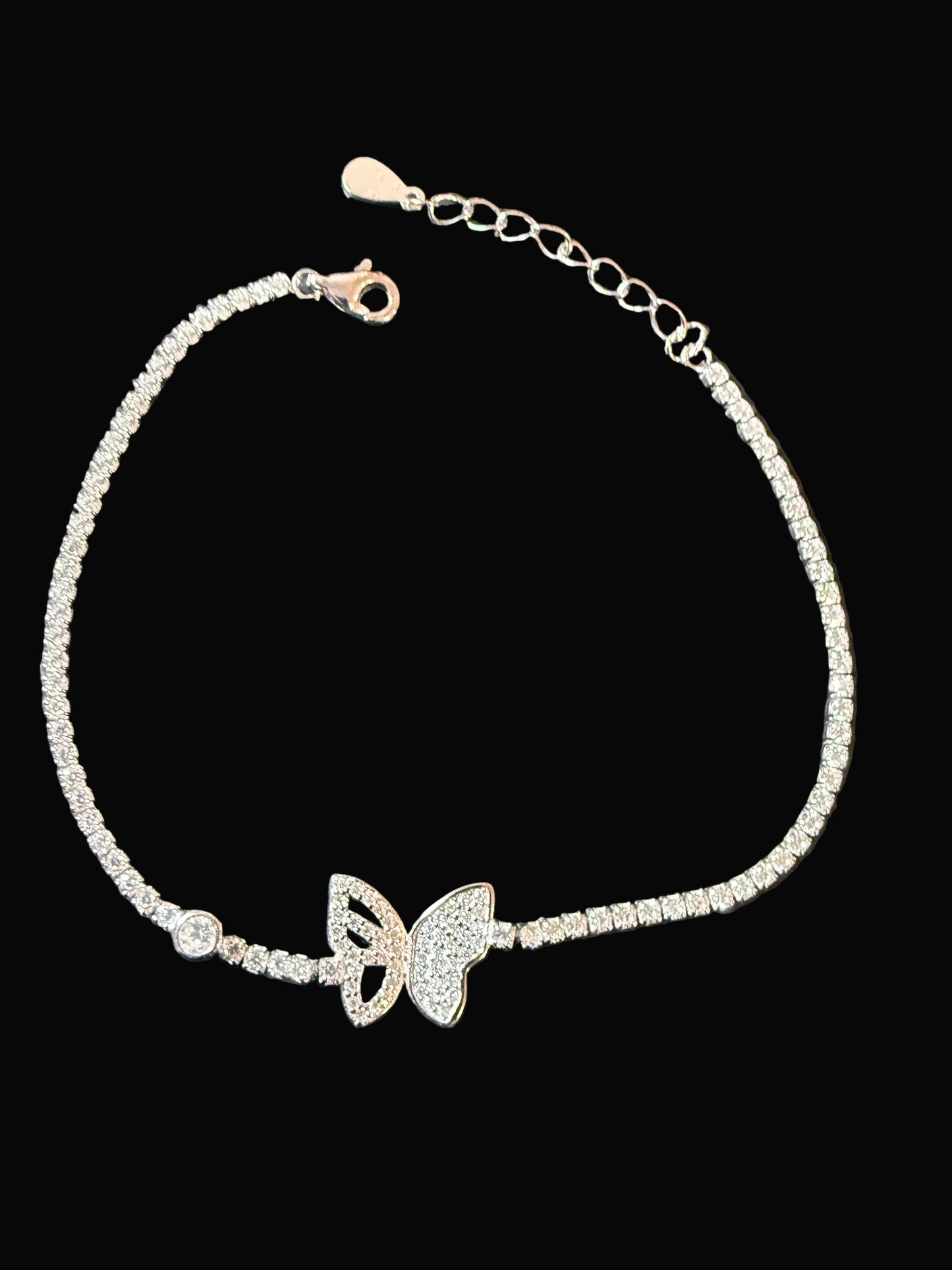 Silver bracelet with butterfly charms on a dark surface