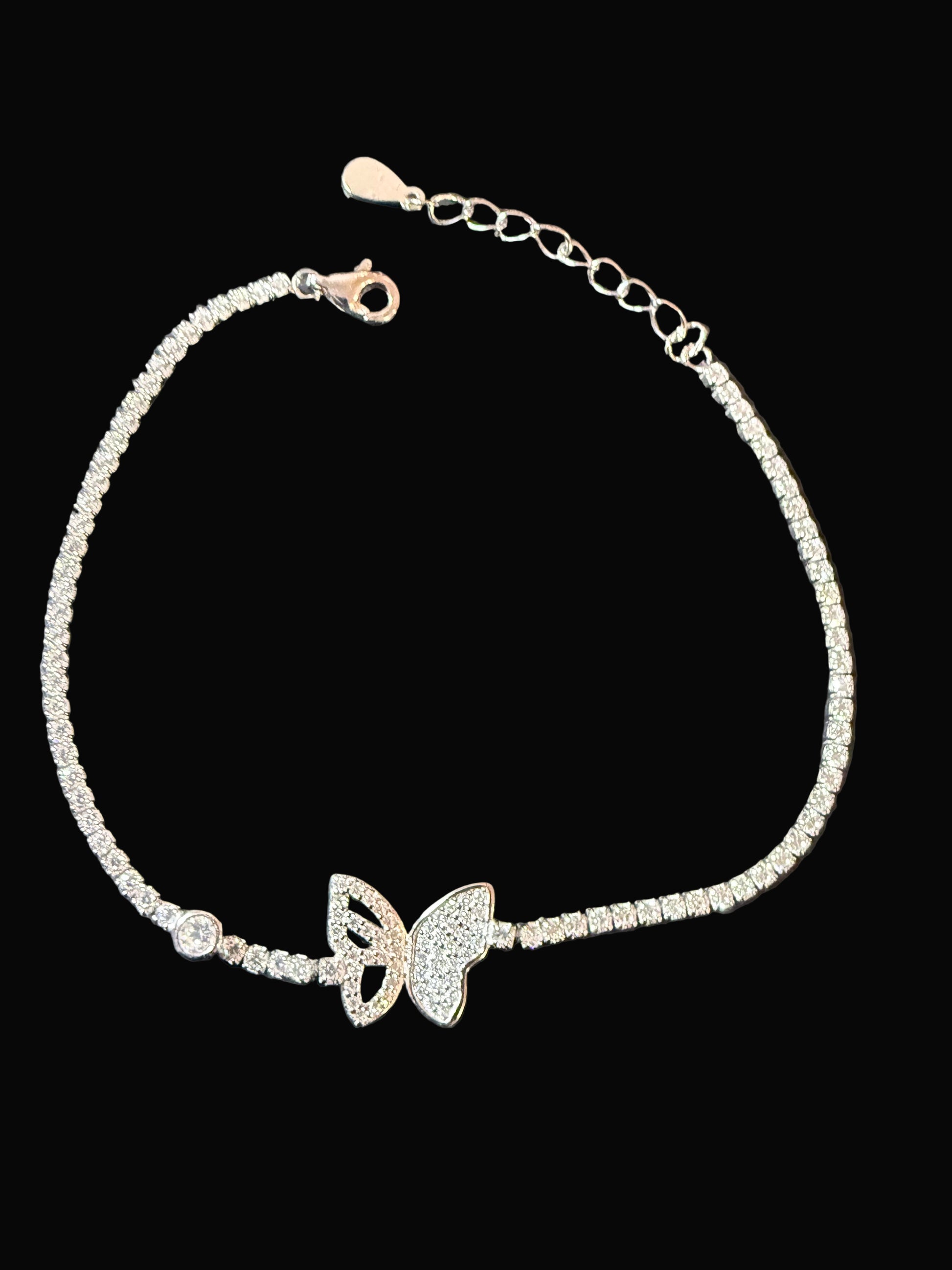 Silver bracelet with butterfly charms on a dark surface