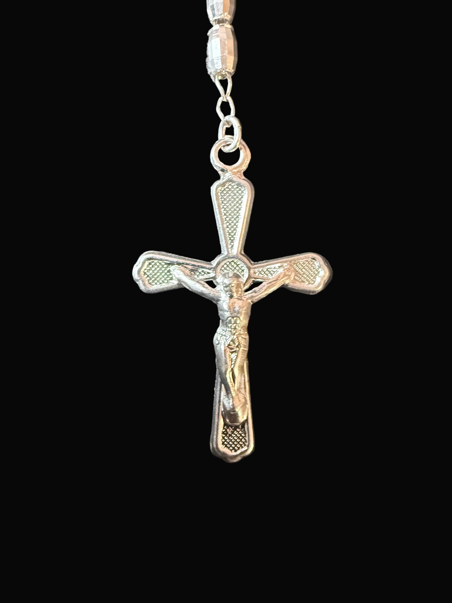 Silver cross pendant on a chain against a dark background